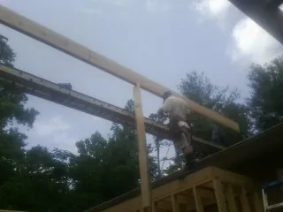 Carpenter setting a ridge beam over a new addition frame — Ice Dam Removal by Roofing Brothers in Minoa