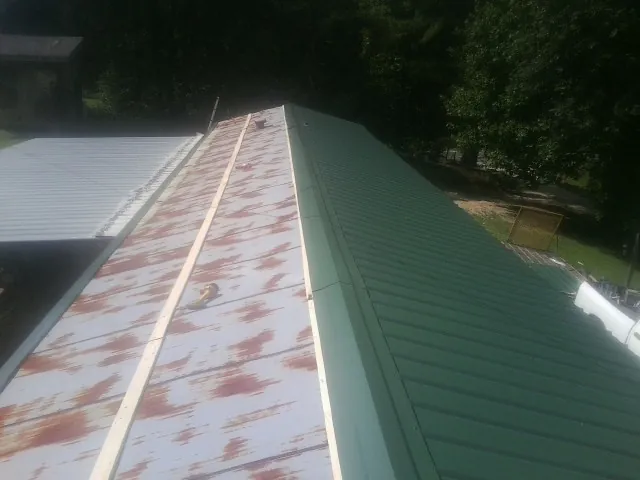 Old rusted panels beside newly installed green metal roofing — Wind Damage Roof Repair by Roofing Brothers in Minoa