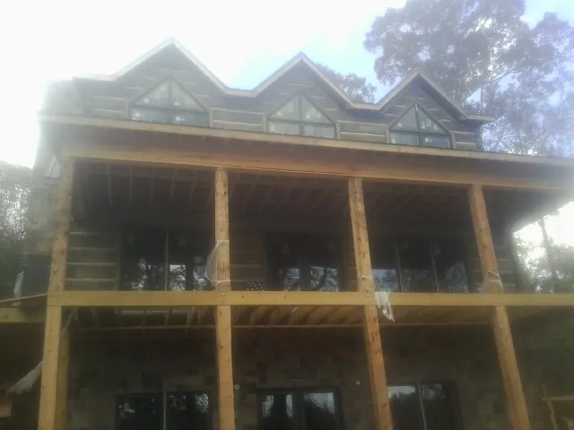 Dormers and porch framing on a large log home under construction — Roof Coating work by our crew in Minoa