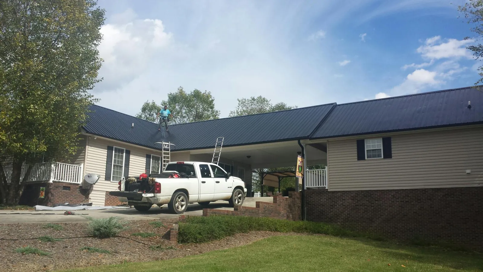 Black metal roof over a home and attached breezeway with ladders set in Minoa