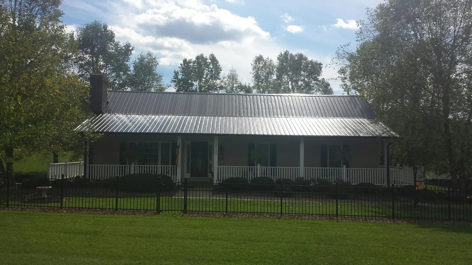 Gray metal roof on a brick ranch with a full width front porch — Gutter Guard Installation work by our crew in Minoa