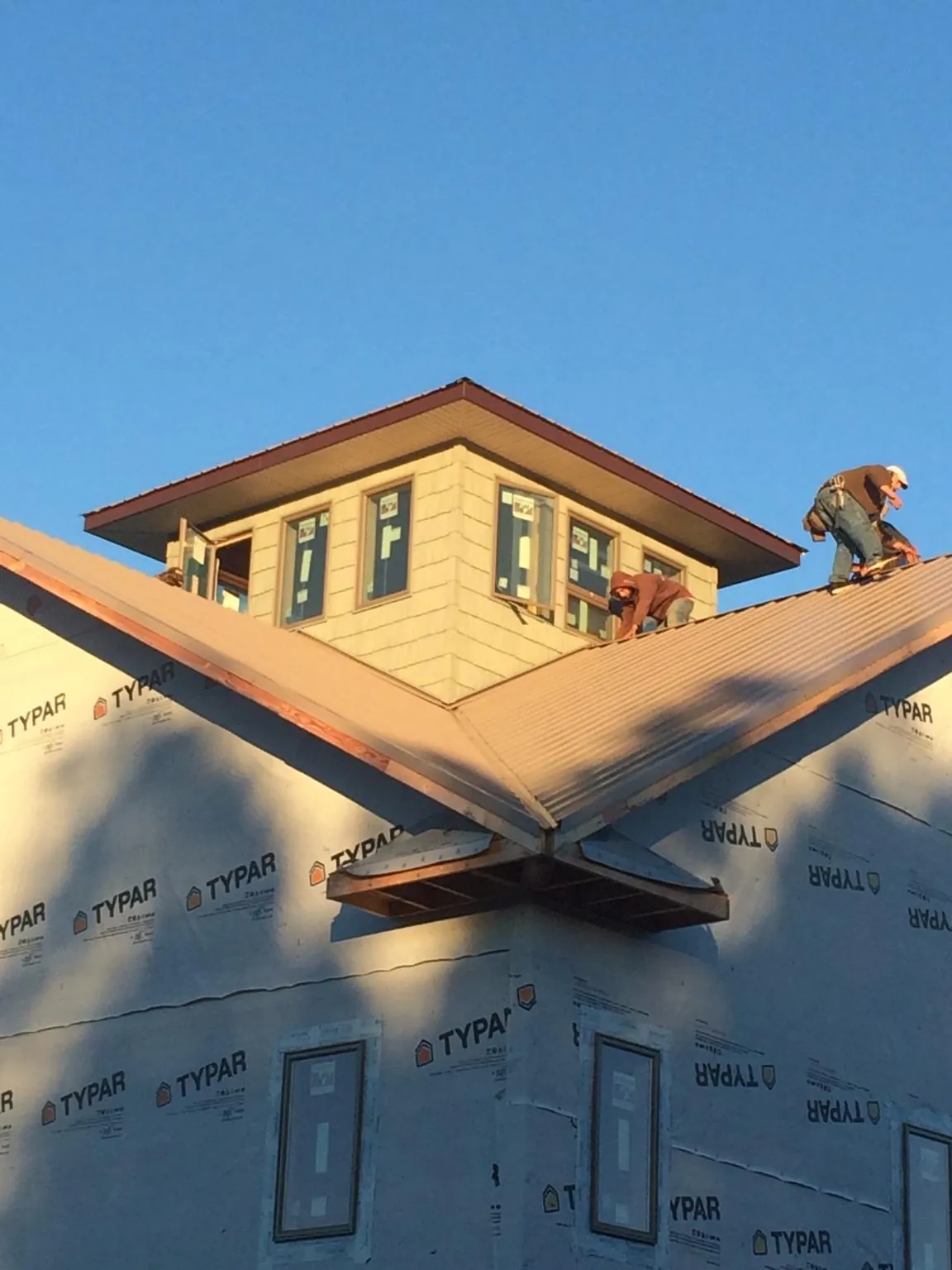 Roofers working around a rooftop cupola on a new metal roof at sunset — Roof Waterproofing in Minoa by Roofing Brothers